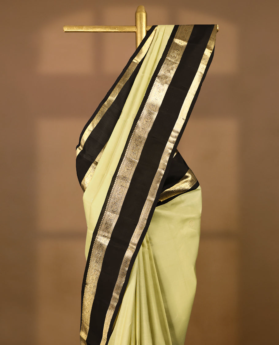 Key lime Colour pure traditional Kanchipuram silk saree adorned with intricately woven antique zari Chakkram motifs on the body, complemented by a Contrast black traditional border featuring Chakkram designs, and paired with a matching blouse.