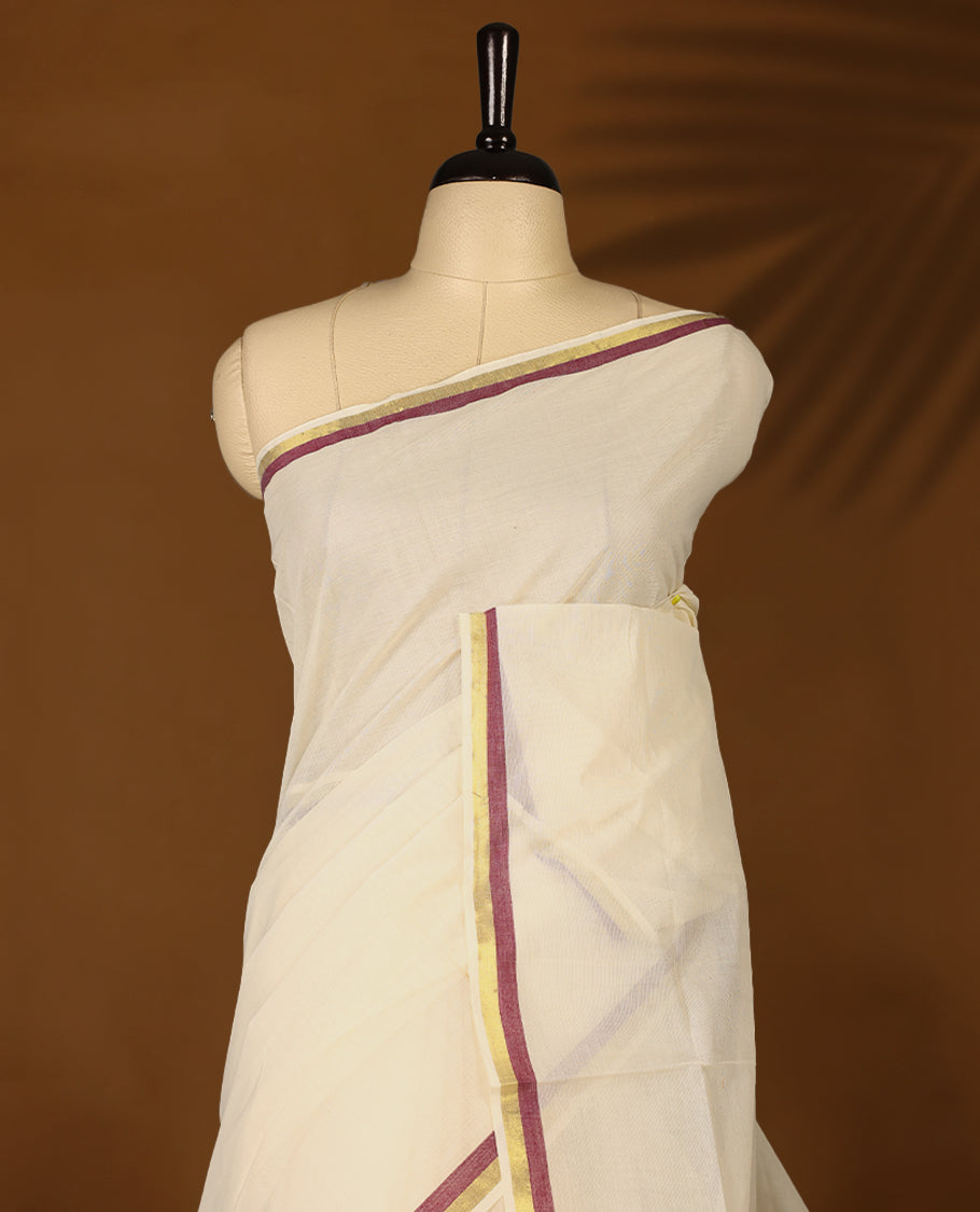 Elegant off white colour cotton Kerala saree featuring a plain body and traditional golden zari border with a hint of Grape purple, offering a classic and graceful look, paired with a matching blouse.