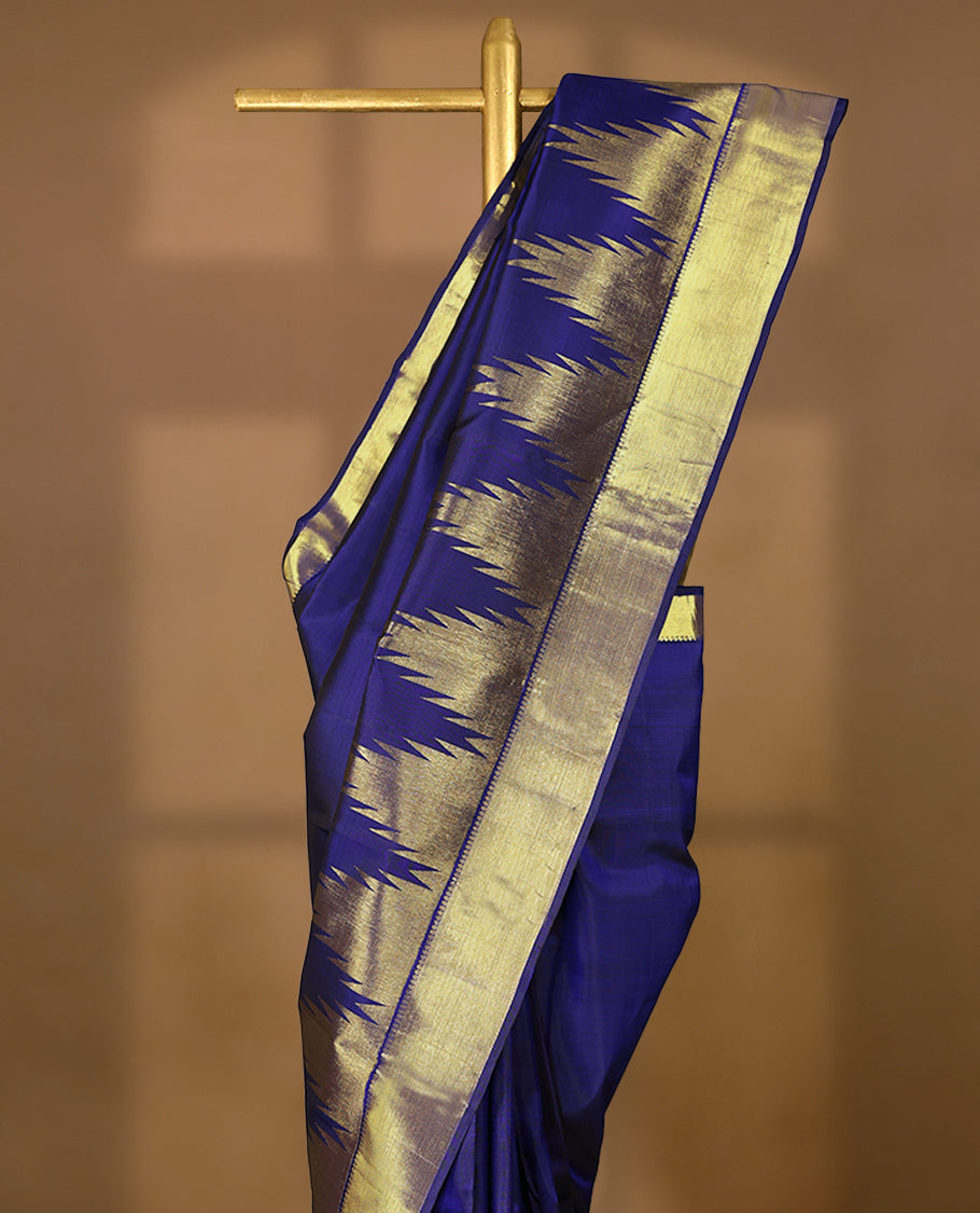 Navy blue pure traditional Kancheepuram silk saree featuring a plain body, complemented by a traditional border adorned with temple motifs, and paired with a matching blouse.
