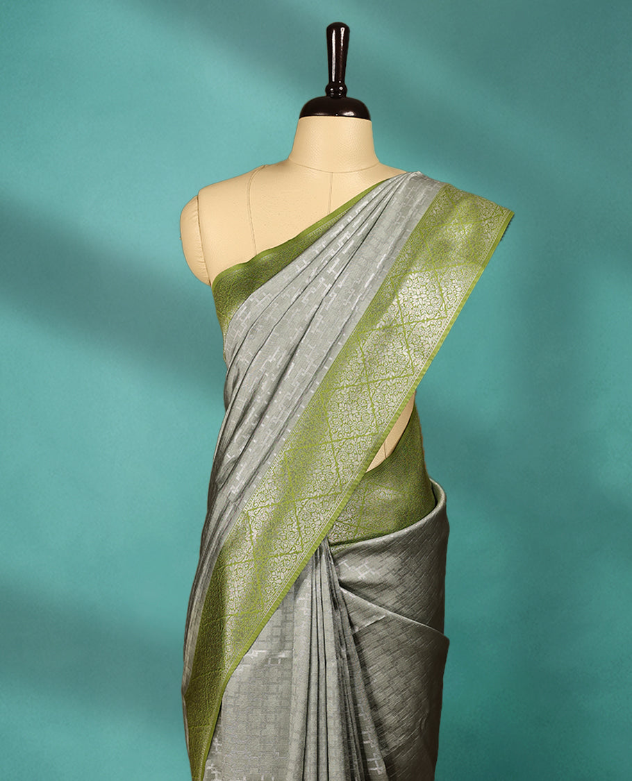 Greenish Grey coloured semi silk saree featuring a Zari design on the body, paired with a Green coloured border and matching blouse.