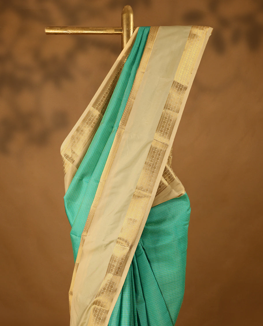 Aqua blue and green Colour soft silk saree adorned with golden zari stripes on the body, complemented by a contrasting traditional border, and paired with a matching contrast coloured blouse.