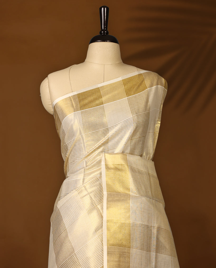 Elegant tissue Kerala saree with a cream base and golden checkered pattern, complemented by a rich golden zari border & Paired with a matching blouse, it's perfect for festive and traditional occasions.