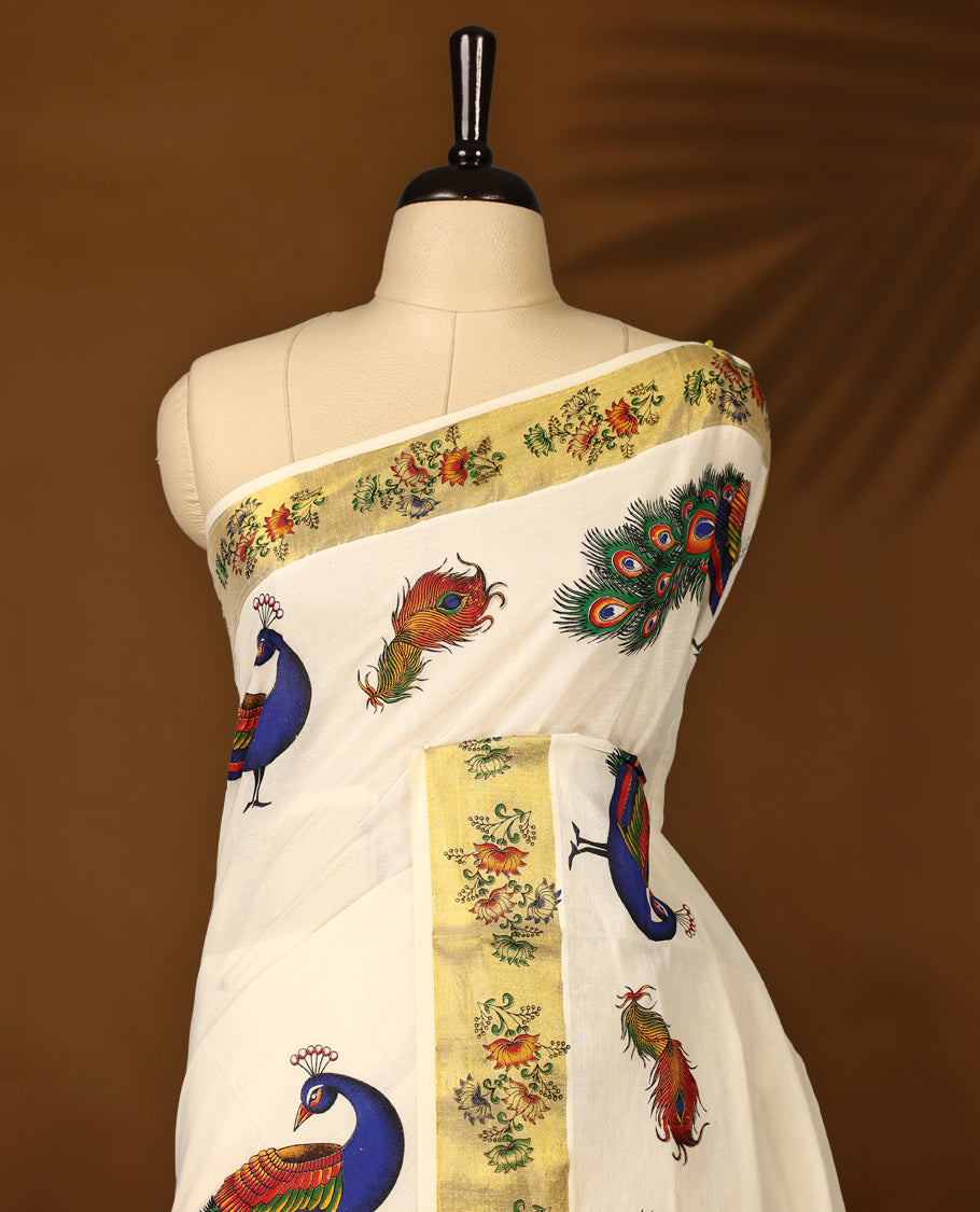 Elegant off white colour cotton Kerala saree with vibrant hand-painted peacock and feather motifs, accented by a floral printed golden border and pallu, paired with a matching blouse for a festive, graceful appeal.