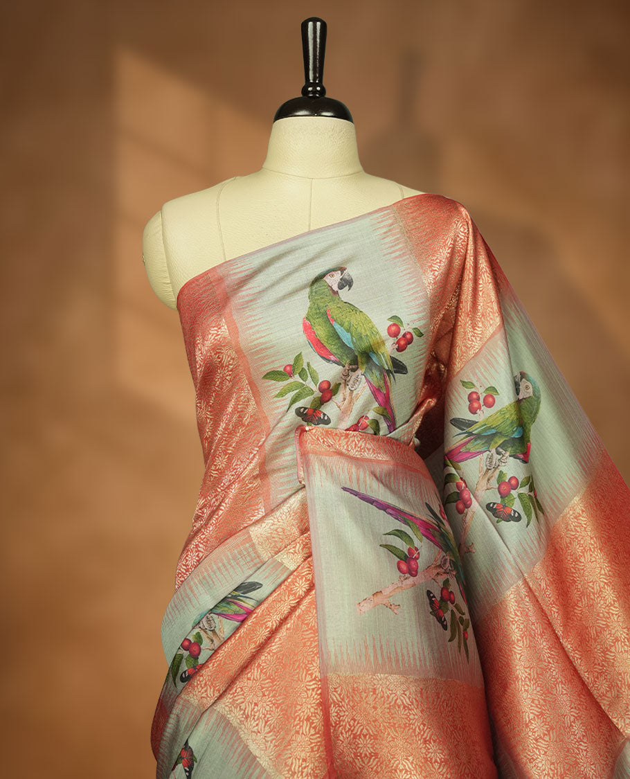 Peach and pastel green semi tussar Banarasi saree featuring artistic parrot prints perched on berry-laden branches across the body, with gold geometric woven patterns, an elegant peach zari border, and a matching blouse.