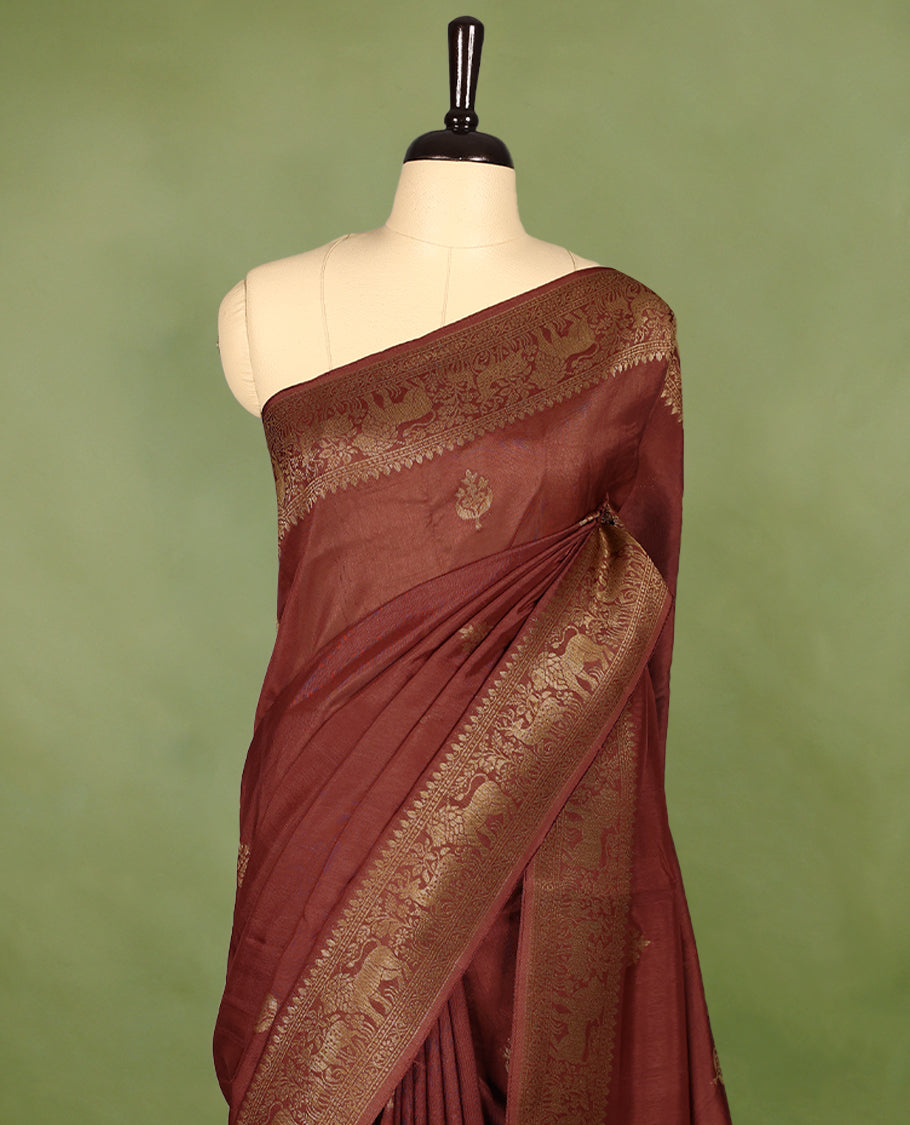 Rust Orange semi-Banaras tussar georgette saree adorned with antique zari butta motifs on the body, accentuated by a beautifully crafted jungle-themed border, and paired with a matching blouse.