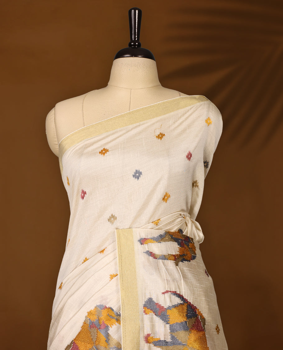 Cream colour Tussar saree adorned with multicolour geometric elephant motifs and delicate thread buttas across the body, enhanced with a subtle gold zari border, paired with a matching blouse.