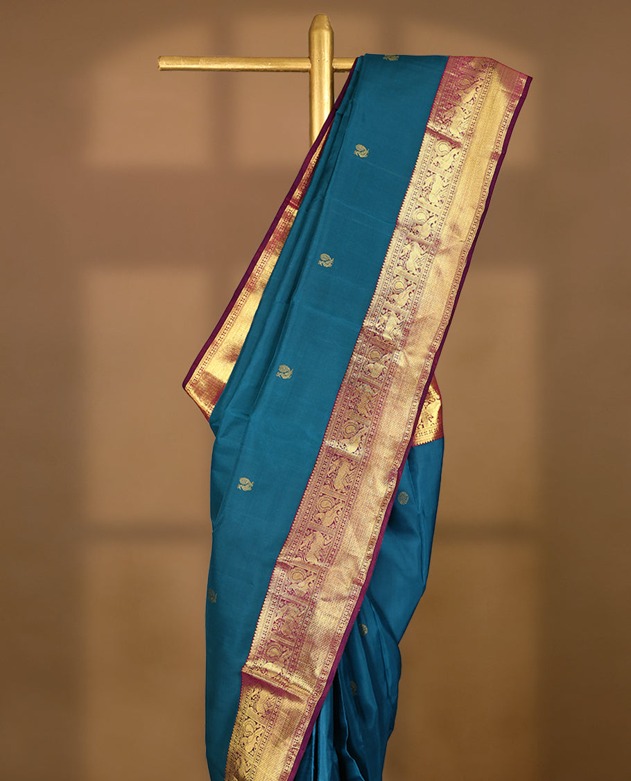 Blue Colour pure traditional Kancheepuram silk saree featuring antique zari peacock and chakkram motifs on the body, complemented by a traditional contrast coloured border and a matching contrast blouse.