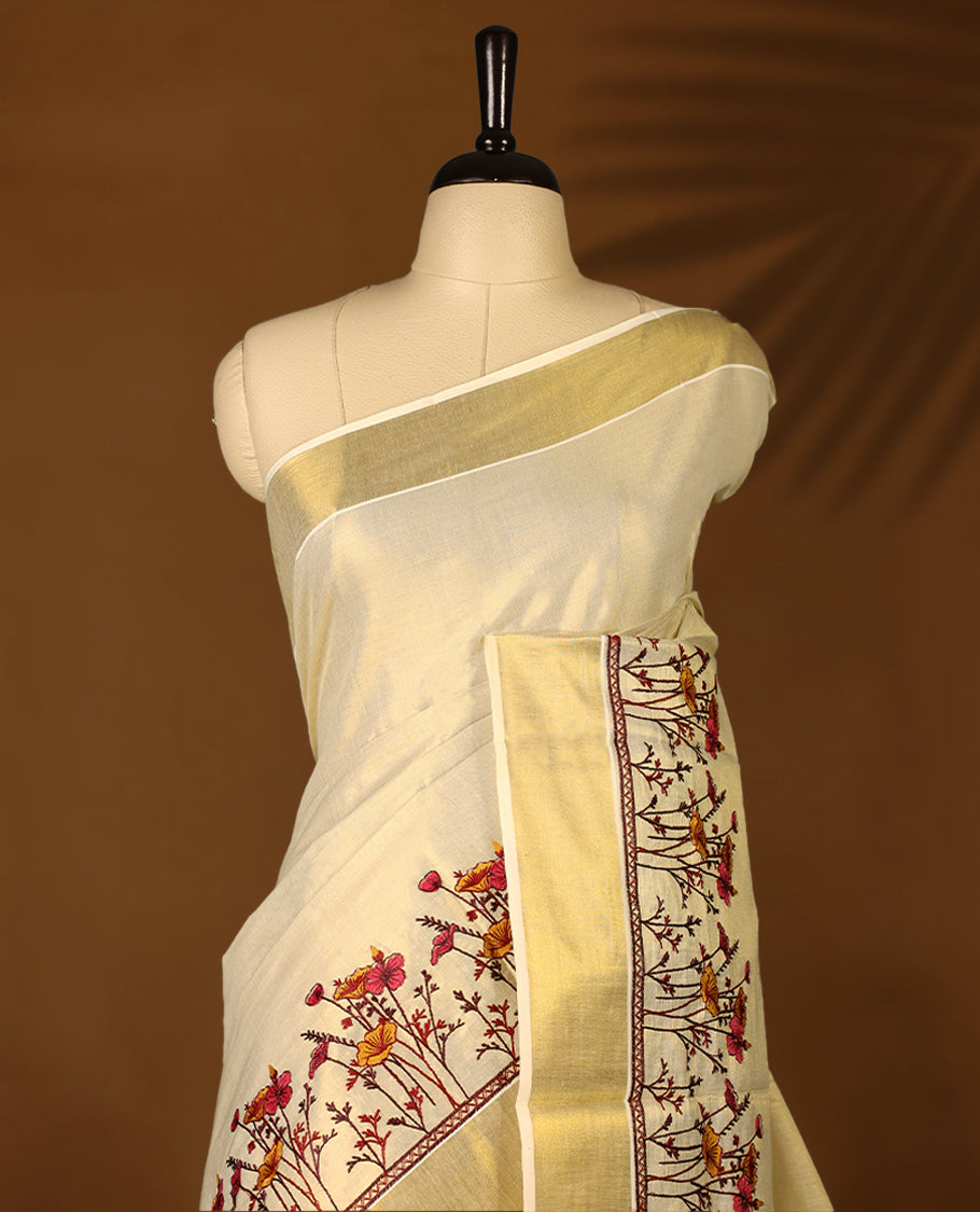 Light Gold colour Tissue Kerala saree featuring Plain body and a beautifully woven Gold Kasavu border with Heavy Floral embroidery work, paired with a matching blouse perfect for festive occasions.