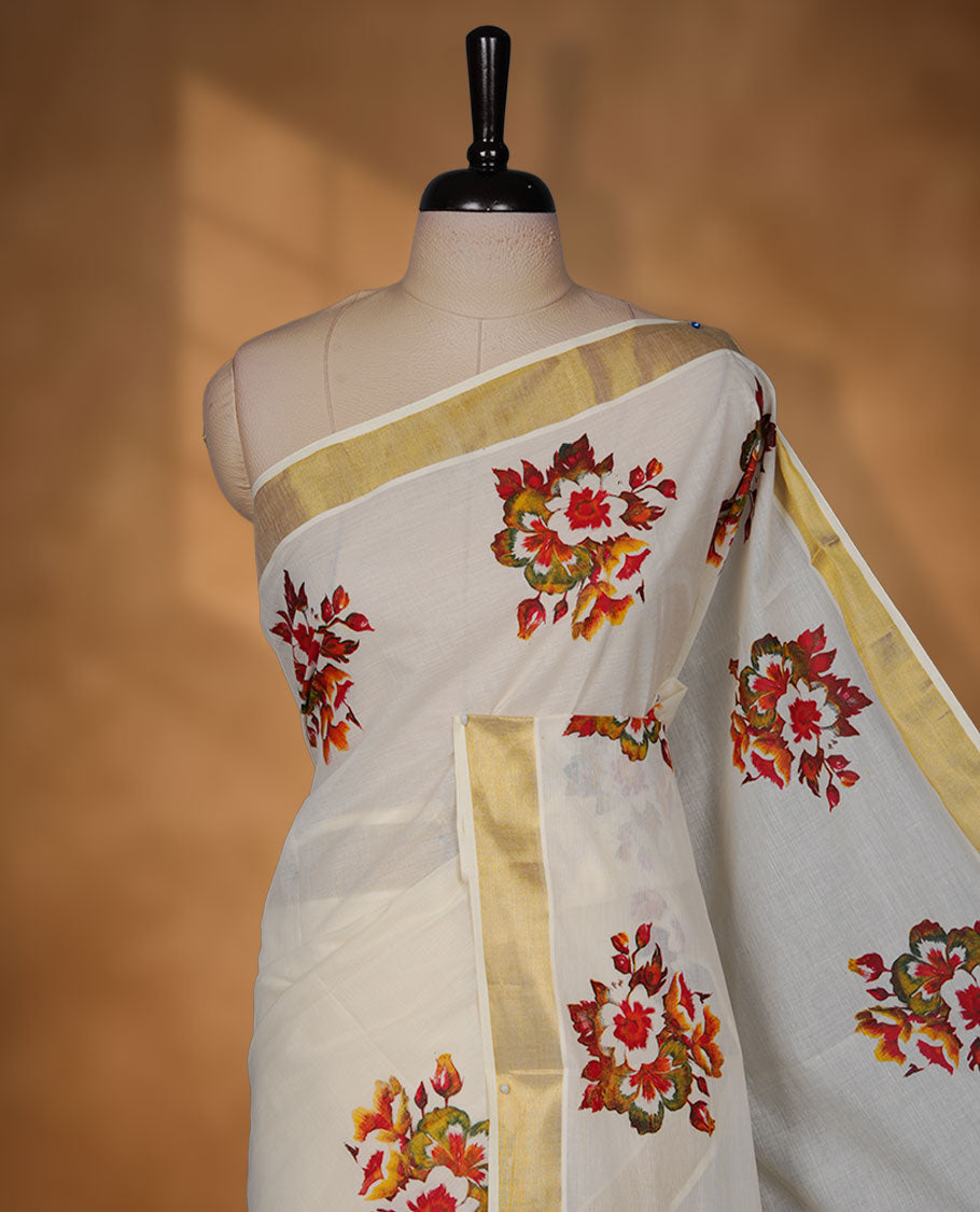 Off-white colour cotton Kerala saree with a classic gold kasavu border, adorned with multicolour floral motifs across the body and pallu, and paired with a matching blouse.
