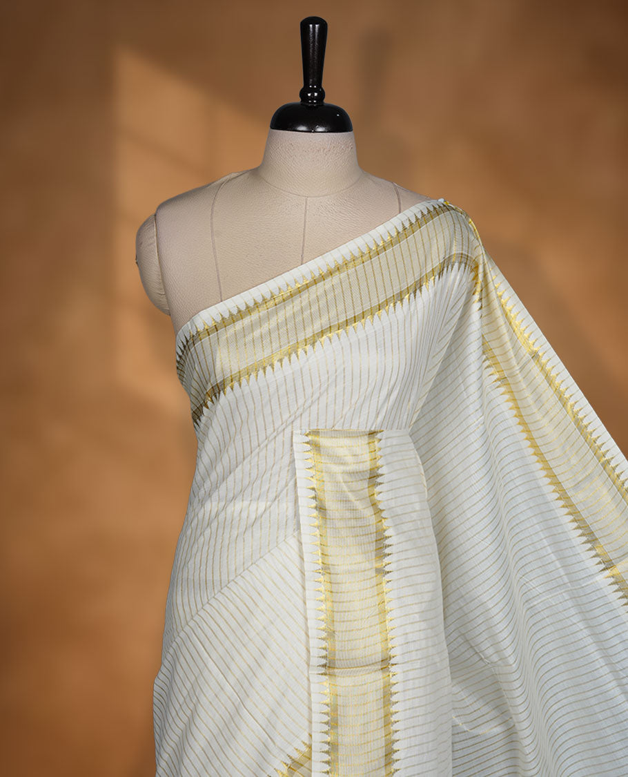 Off white colour cotton Kerala saree featuring fine golden striped motifs, complemented by a classic golden zari border and traditional pallu, paired with a matching blouse.