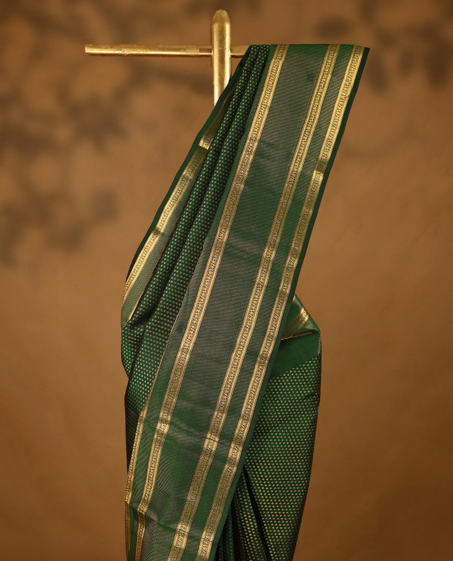 Bottle green Colour soft silk saree adorned with delicate golden zari flower motifs, featuring a stunning Neli Kamalam design border complemented by a plain blouse in a matching self-tone colour