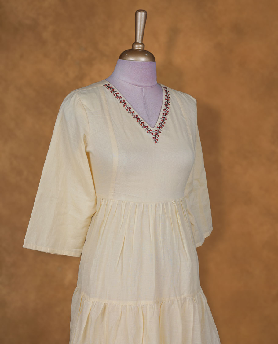 Soft cream yellow colour kurti BY VISMAY with floral printed hem, featuring a V neckline with embroidery, three quarter sleeves, and a tiered knee length silhouette.