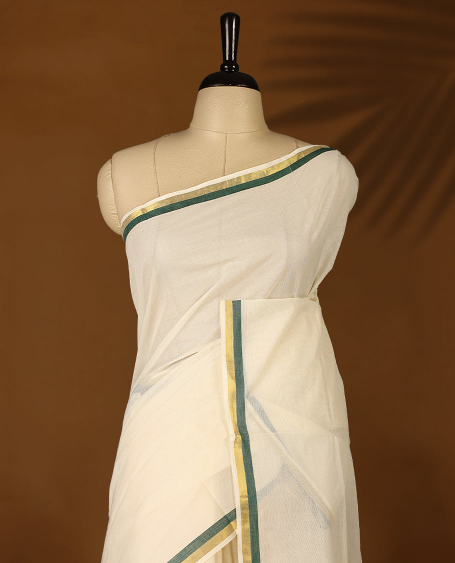 Elegant off white colour cotton Kerala saree featuring a plain body and traditional golden zari border with a hint of Deep Green, offering a classic and graceful look, paired with a matching blouse.