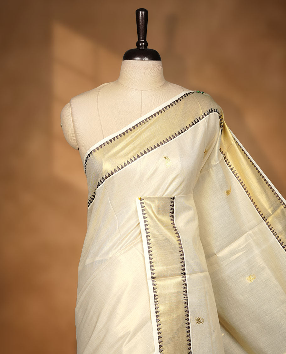 Light gold colour tissue Kerala saree featuring delicate gold zari buttas across the body, finished with a classic kasavu border highlighted by black triangle detailing, paired with a matching blouse.
