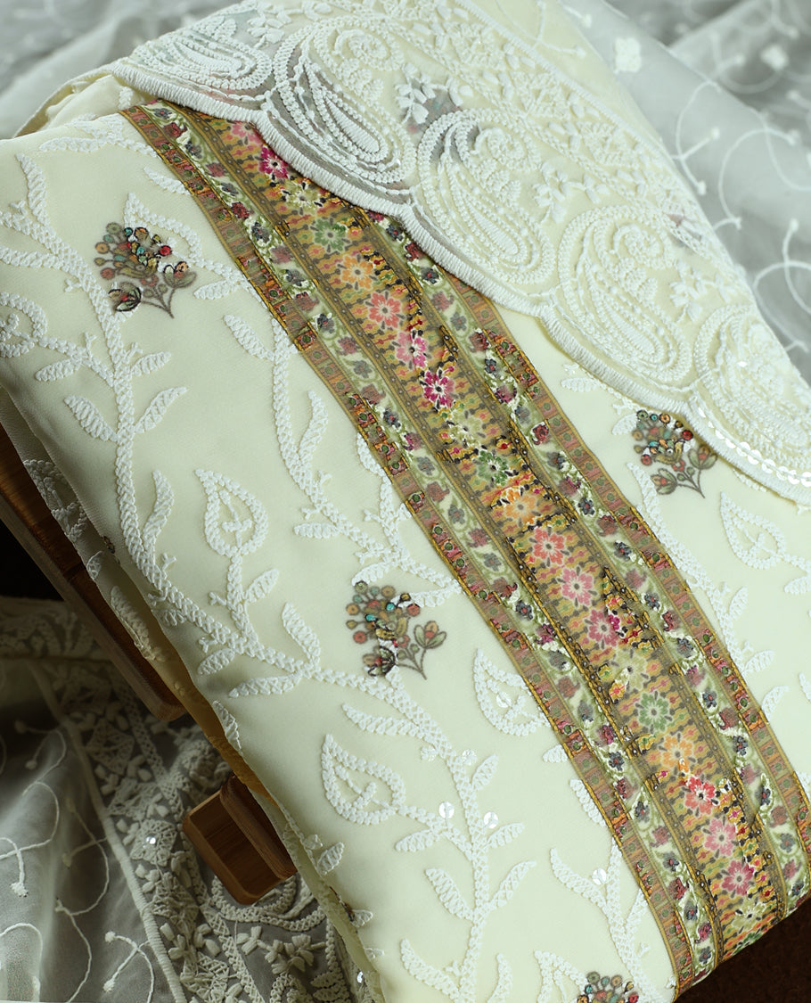 Cream colour churidhar material with heavy embroidered neck work, delicate floral motifs on the body, and multicolor panel detailing & Comes with matching plain bottom and embroidered net dupatta.