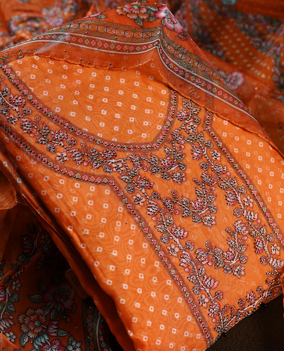 Vibrant orange churidhar material enhanced with delicate floral,stone and vine prints, paired with a plain matching bottom and a beautifully printed dupatta, perfect for festive elegance and traditional charm.
