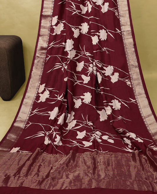 Maroon colour Viscos semi printed saree featuring a golden zari border, white floral printed motifs across the body, and comes with a matching blouse