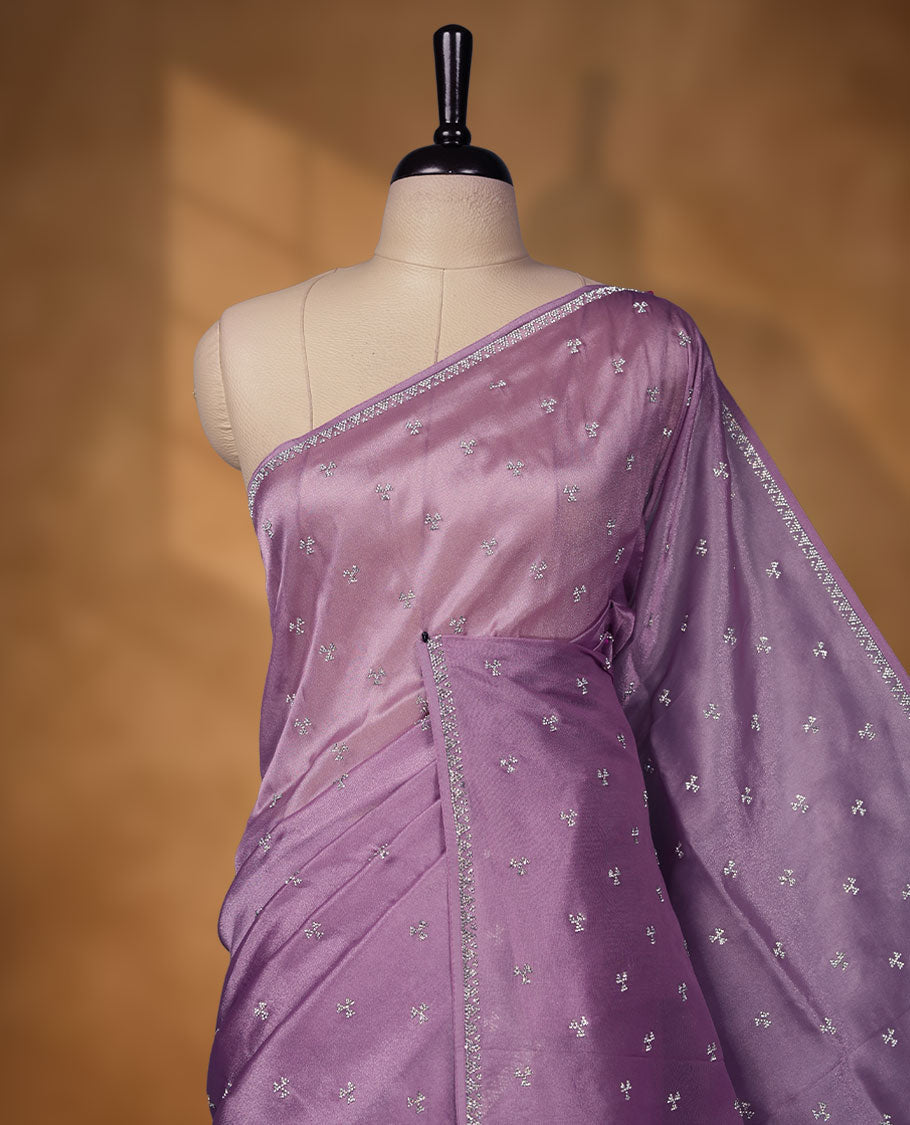 Lavender Colour net shimmer fancy saree adorned with scattered white stone buttas all over the body, paired with a delicate stone worked border and matching blouse.
