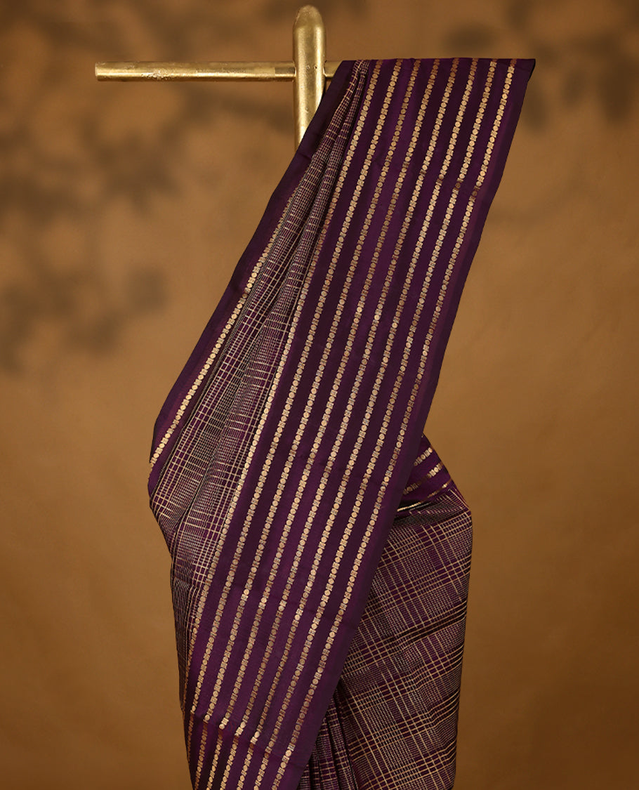 Grape wine Colour soft silk saree adorned with golden zari checks on the body, complemented by a self-coloured border featuring a golden zari Poun design, paired with a matching self-coloured blouse