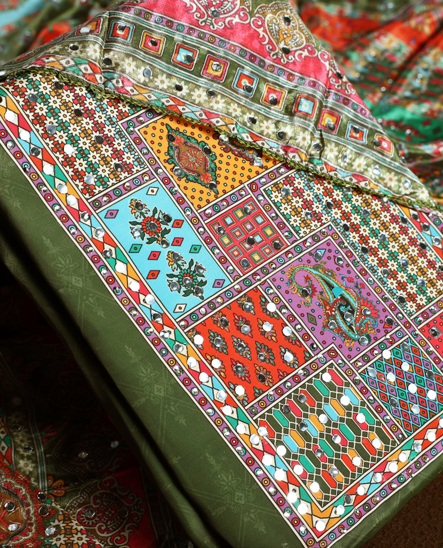 Elegant olive green churidhar material with vibrant multicolour geometric and paisley prints, enhanced with delicate mirror work, paired with a plain matching bottom and bold printed dupatta, perfect for festive occasions.