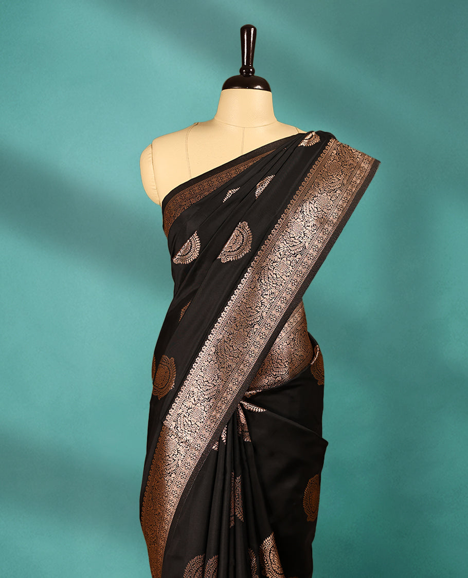Black coloured semi silk saree featuring a Golden Zari Butta design on the body, paired with a Self coloured border and matching blouse.