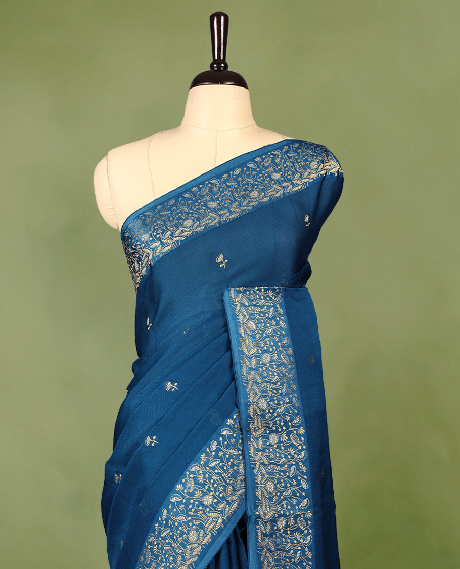 Peacock Blue colour pure Banaras crepe saree showcases elegant Gold zari Flower Motifs all over the body, a traditional gold & Silver zari border, a rich intricately woven pallu, and comes with a matching blouse.