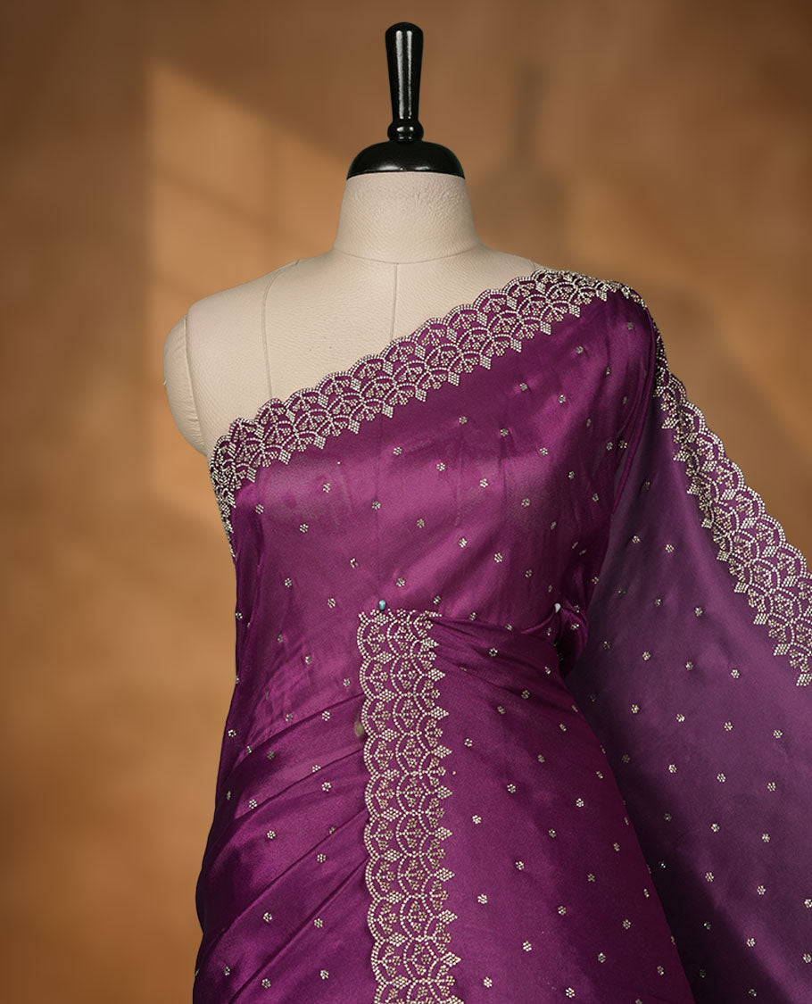 Purple Colour shimmer fancy saree adorned with scattered white stone buttas all over the body, paired with a delicate stone worked border and matching blouse featuring floral vine stone embroidery