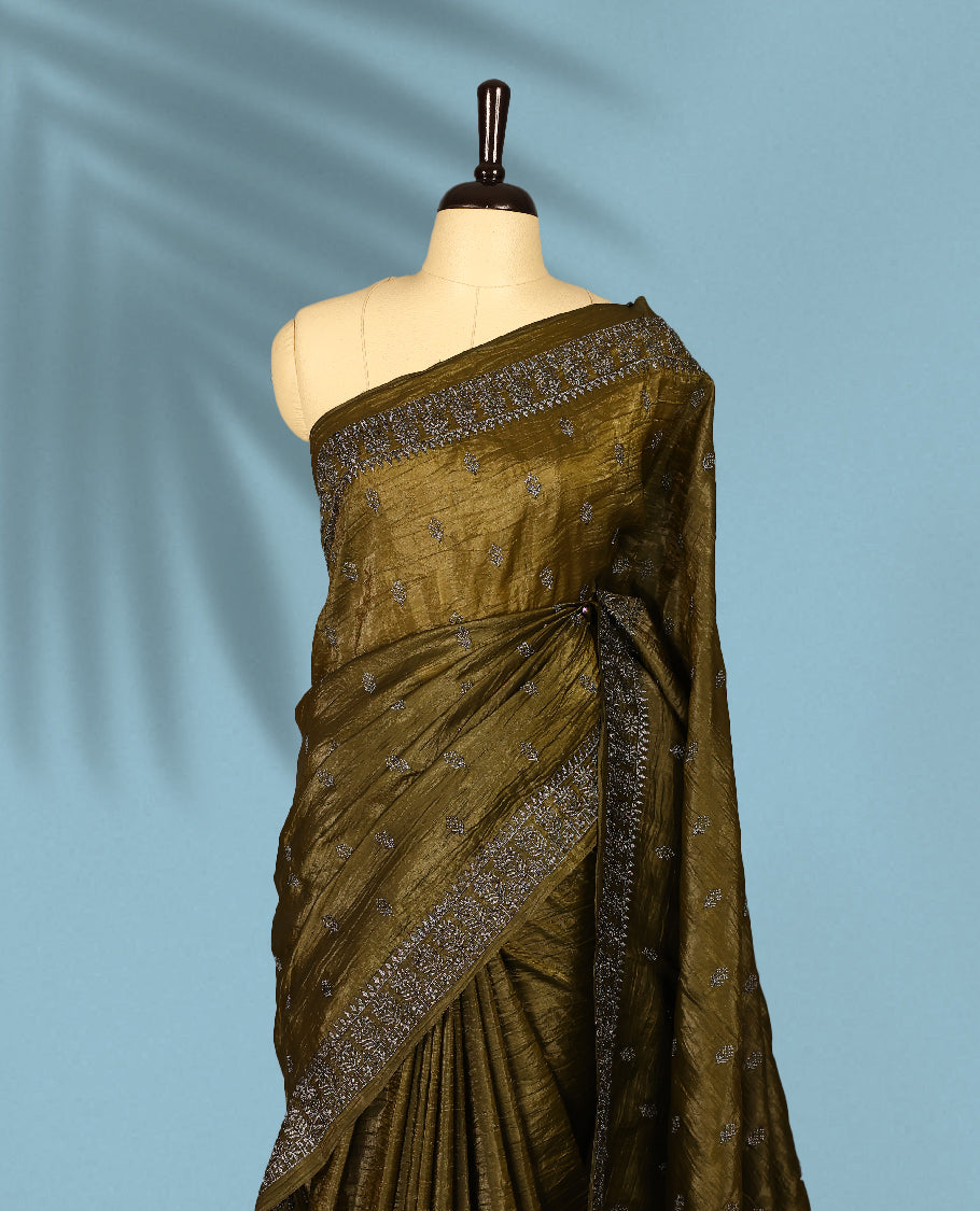 Olive Colour crush soft silk saree, textured body with a natural crinkled finish, adorned with intricate Silver colored floral Motifs and complemented by a delicate Silver Zari embroidery border, paired with a matching blouse