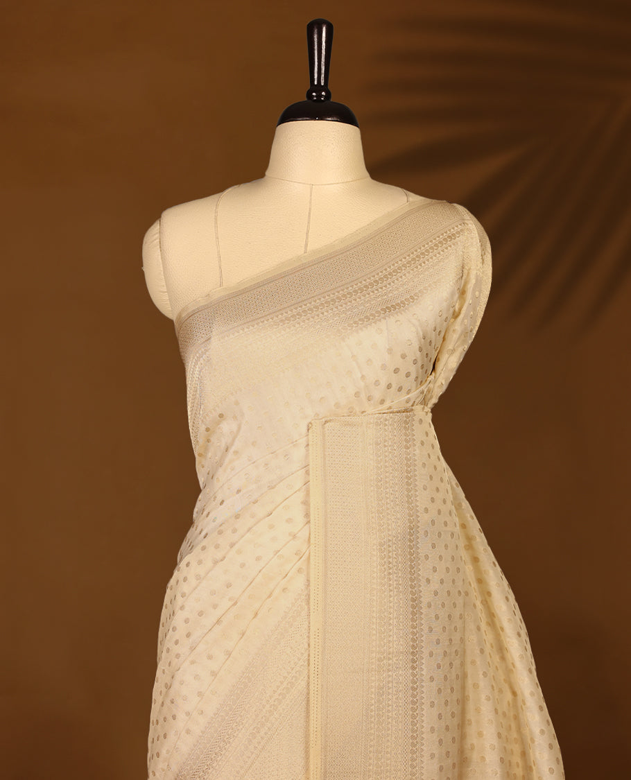 Off white colour georgette Kerala saree featuring intricate dotted woven patterns on the body, complemented by a subtly traditional border and pallu, paired with a matching blouse.