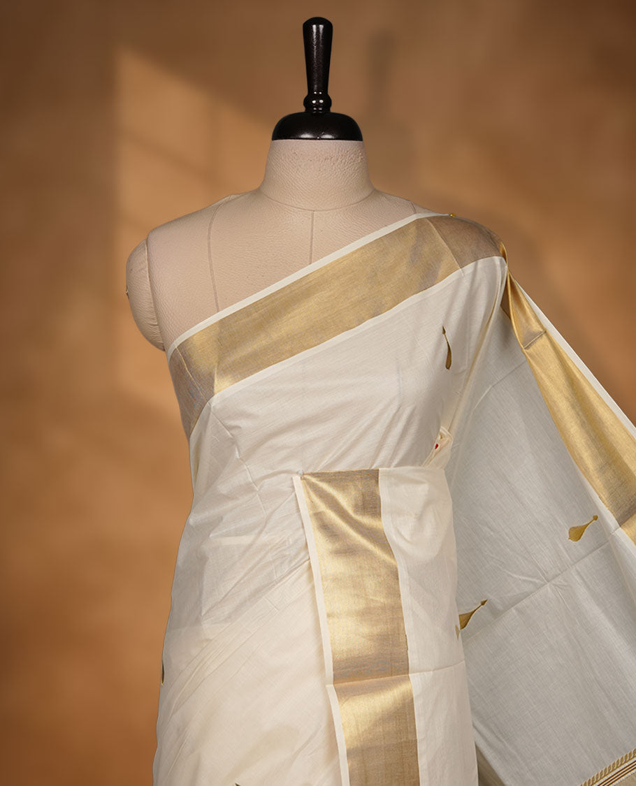Off-white cotton Kerala saree featuring gold zari buttas, a broad kasavu border, and a traditional pallu, paired with a matching blouse.