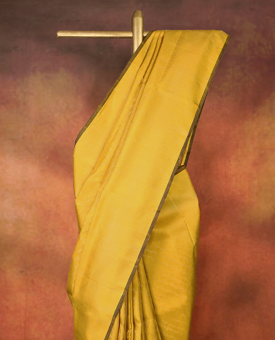 Yellow colour pure Mayuri silk saree featuring finely woven Golden zari motifs across the body, detailed with a subtle geometric self border with intricate texture, with matching blouse