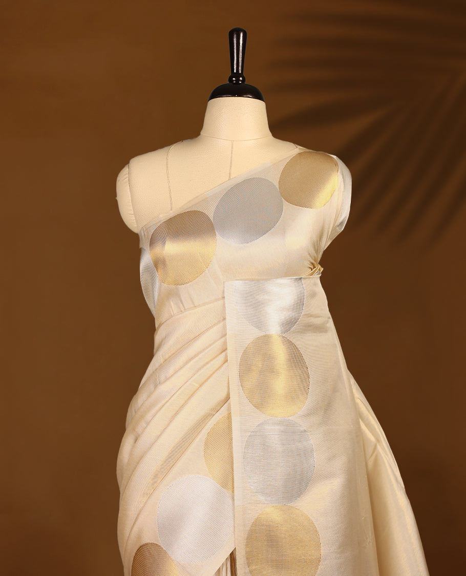 Muted gold Colour soft tissue Kerala saree featuring Plain body, Gold nad silver zari circle motifs on border, paired with a matching blouse.