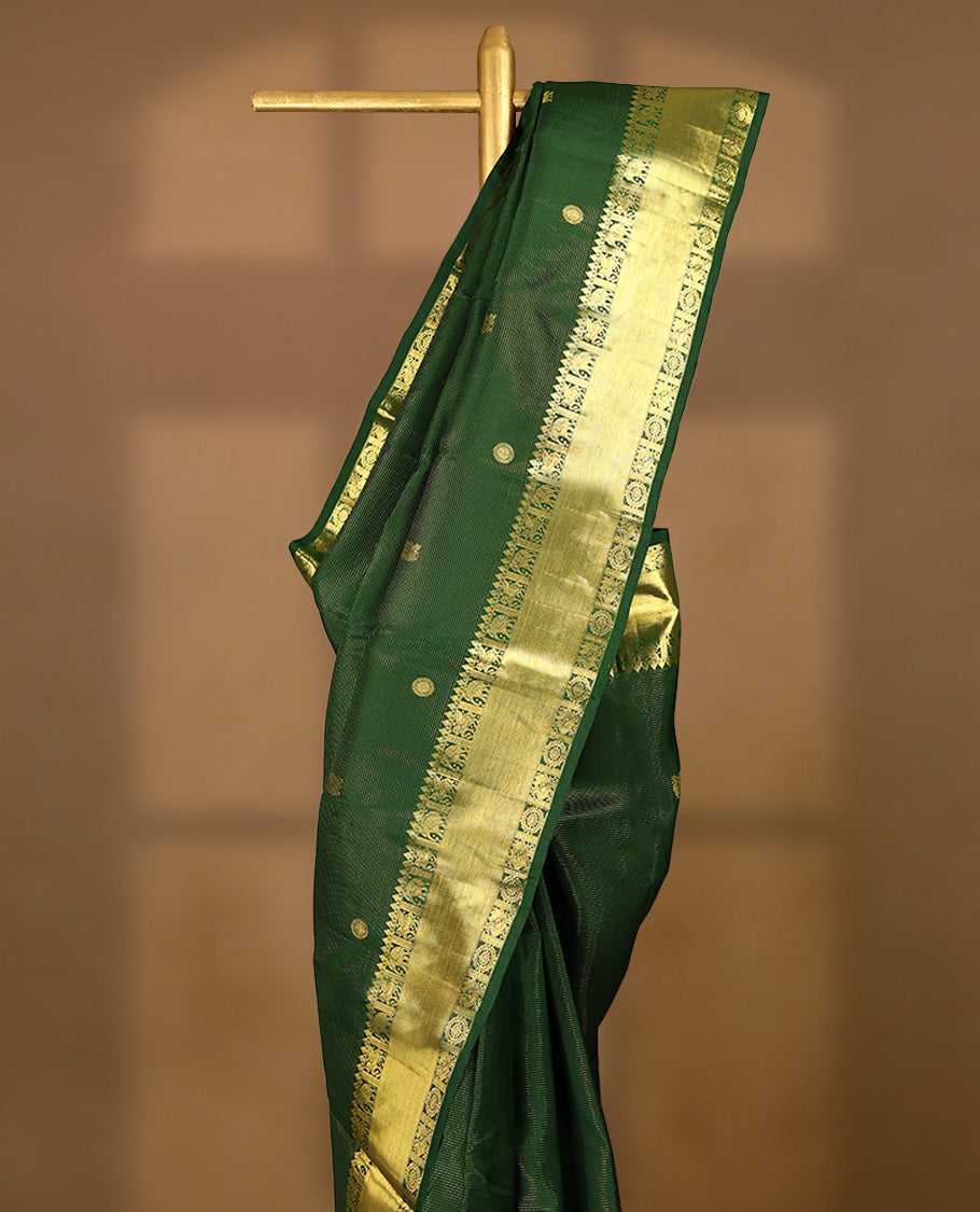 Bottle green Colour pure traditional Kancheepuramsilk saree featuring antique zari peacock and chakkram motifs on the body, complemented by a traditional border adorned with elephant and winged horse motifs, and paired with a matching Blouse