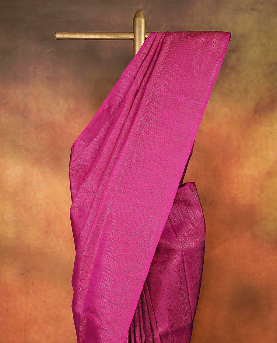 Deep magenta colour pure Mayuri silk saree featuring finely woven Golden zari motifs across the body, detailed with a subtle geometric self border with intricate texture, with matching blouse