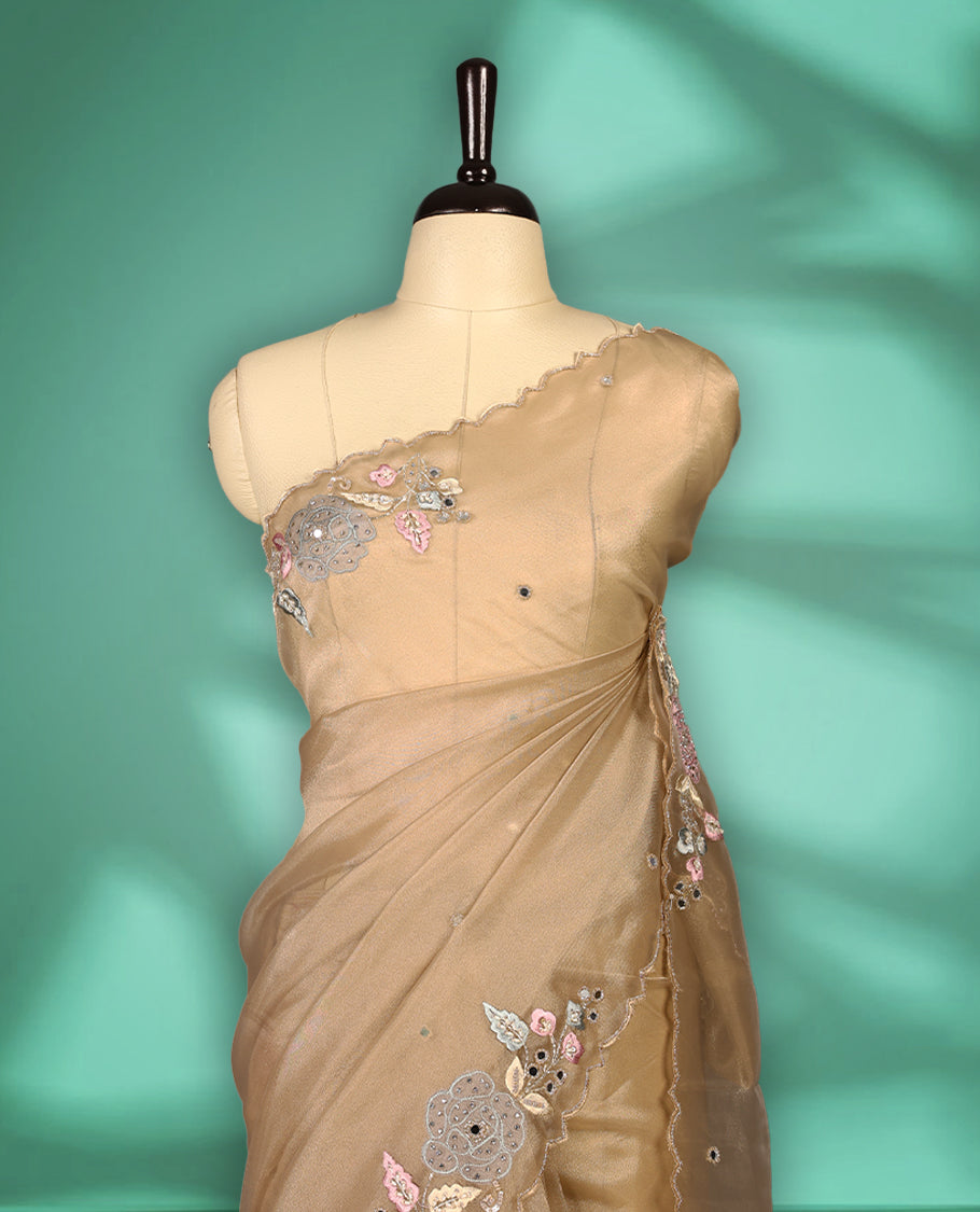 Dusty Pastel Brown colour organza saree featuring delicate floral embroidery with applique bead, mirror, and thread detailing on the body and scalloped border, lending a soft feminine charm, paired with a matching blouse.