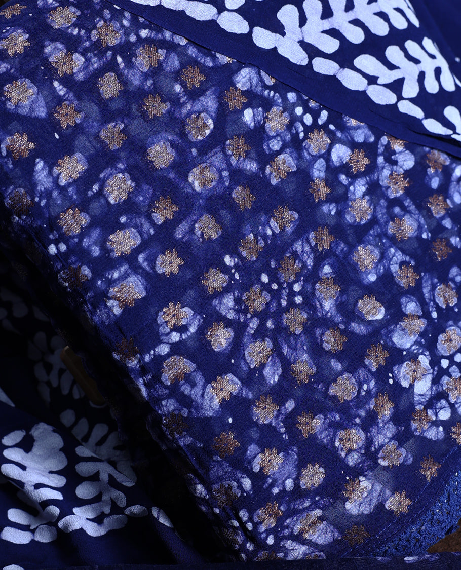 Navy blue colour churidhar material adorned with gold and copper toned floral patterns and bold block designs, paired with a plain matching bottom & Comes with a contrast dupatta featuring bold white leafy block prints.