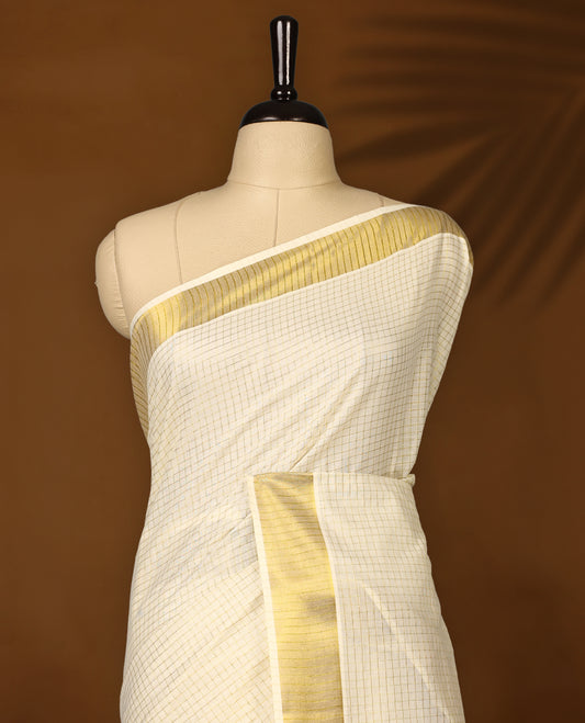 Elegant off white colour cotton Kerala saree with fine checkered patterns and a lustrous golden zari border, Paired with a matching blouse, it’s perfect for traditional functions and festive wear.