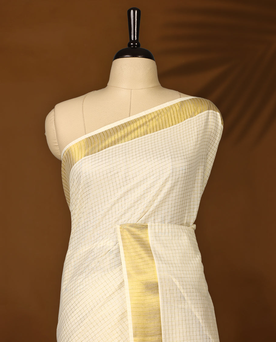 Elegant off white colour cotton Kerala saree with fine checkered patterns and a lustrous golden zari border, Paired with a matching blouse, it’s perfect for traditional functions and festive wear.
