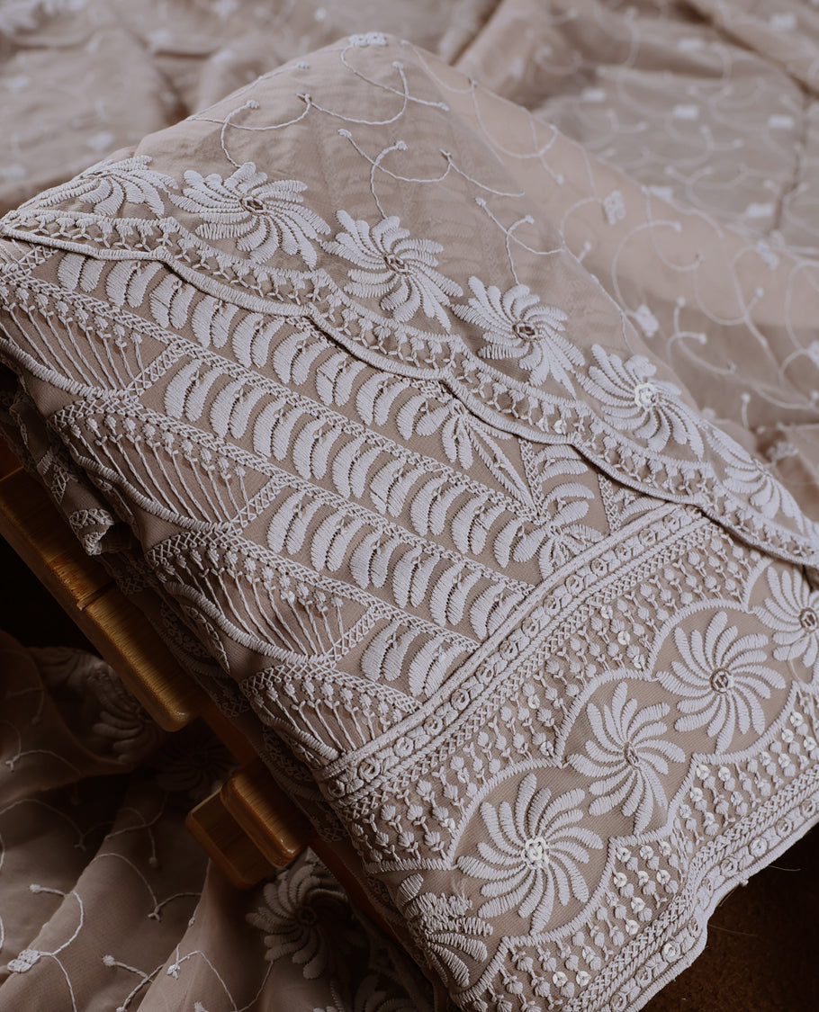 Graceful Taupe colour churidhar material adorned with intricate white floral embroidery and delicate thread patterns, paired with a plain matching bottom and embroidered dupatta, perfect for festive and elegant occasions