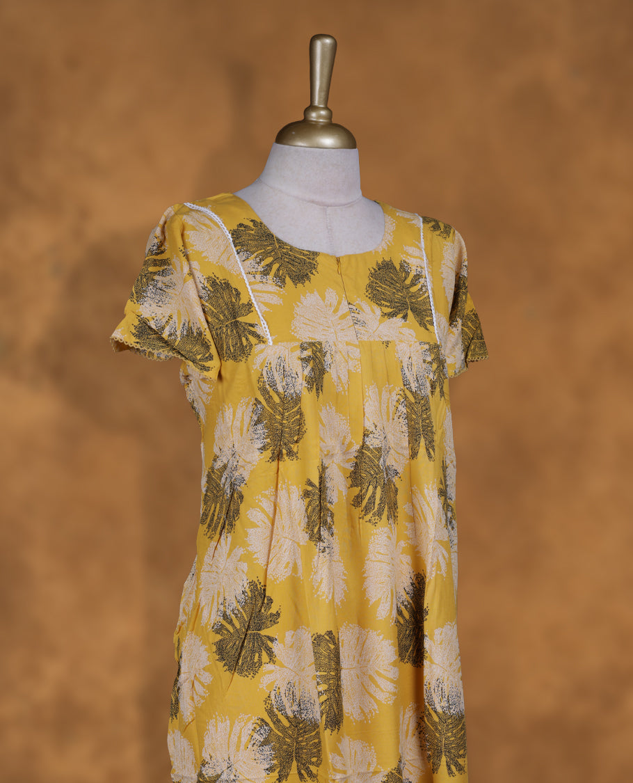 Yellow colour NStyle nighty featuring black and white leaf patterns, a round neckline with gathered detailing, short sleeves, and a full ankle-length design.