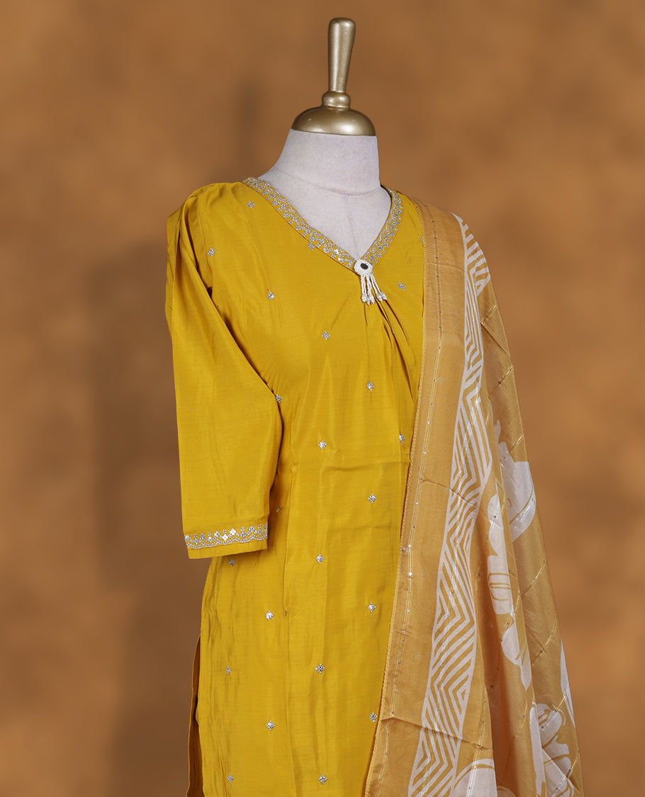 Mustard yellow churidar set featuring V neckline, elbow sleeves, and subtle sequin buttis on body, paired with a coordinated printed dupatta.