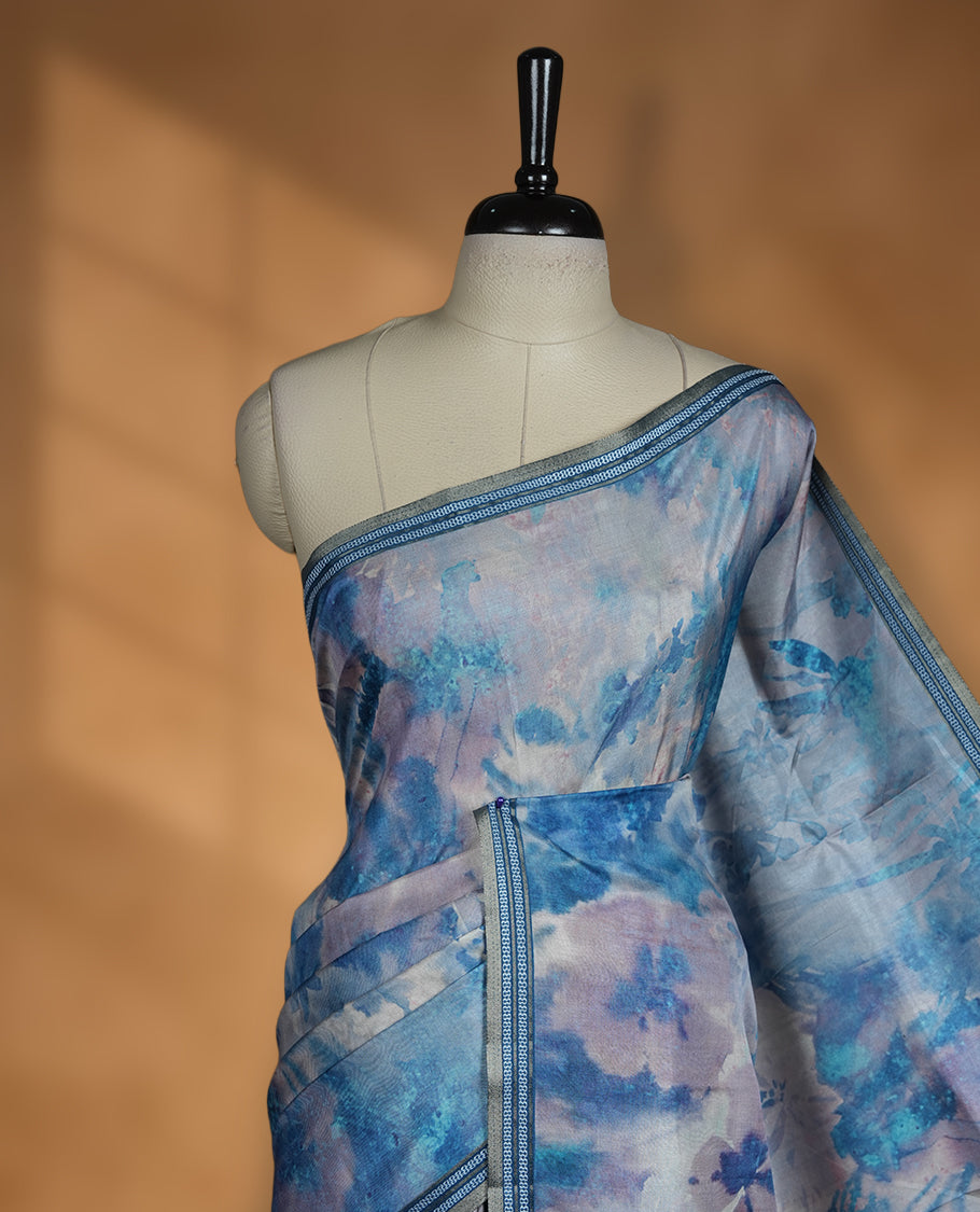 Sky blue colour semi tussar silk saree featuring a dreamy abstract digital floral printed body, finished with a rich self border and tasselled pallu, paired with a matching blouse.
