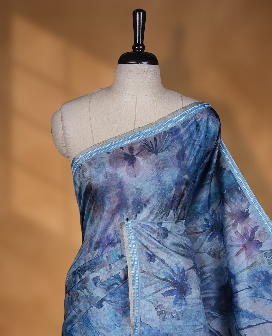 Ocean blue colour semi tussar silk saree featuring an abstract floral printed body with a rich self border and tasselled pallu, paired with a matching blouse.