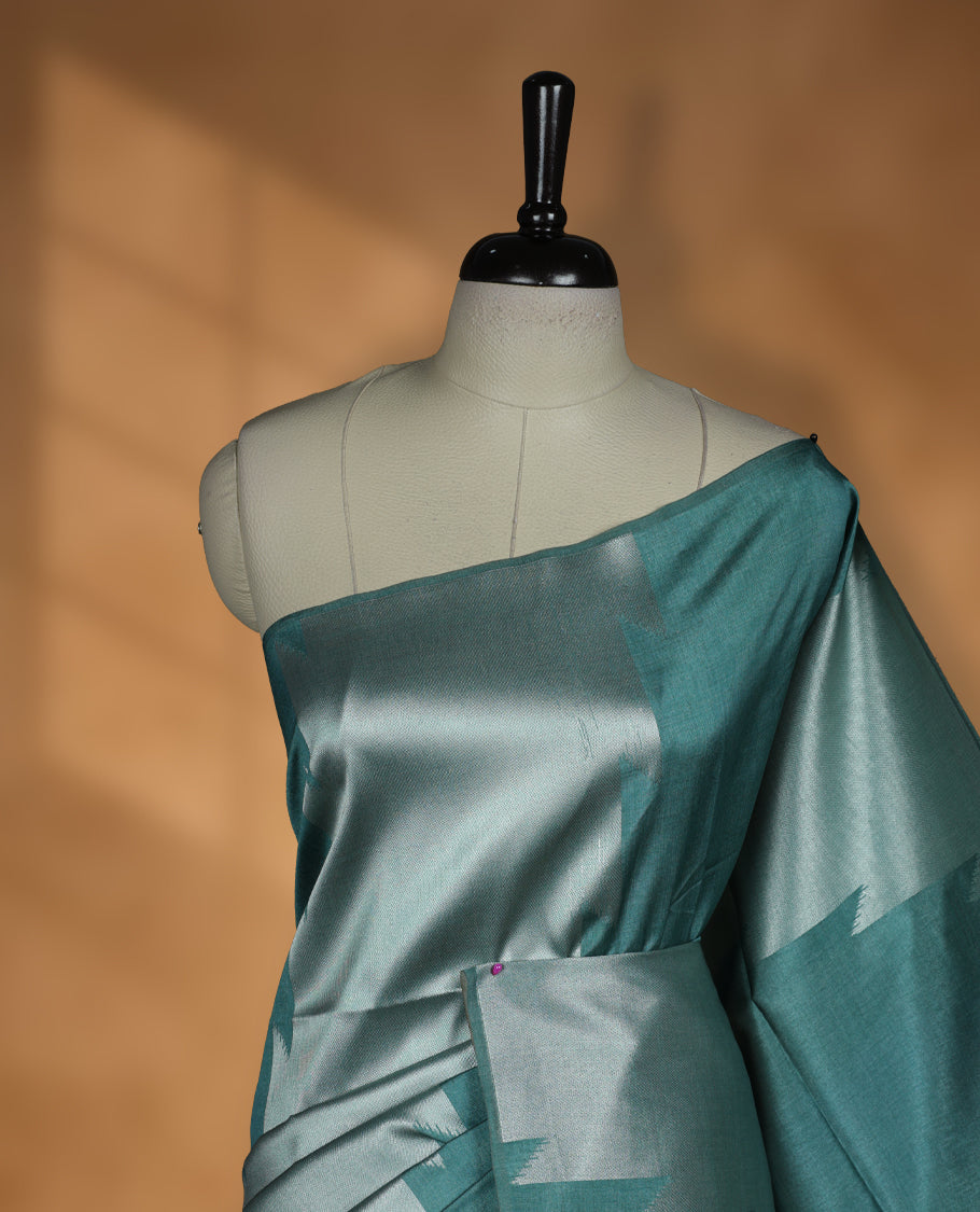 Green and silver dual tone colour semi tussar saree featuring woven abstract geometric motifs on the body, complemented by a ikat inspired patterned pallu, paired with a matching blouse.