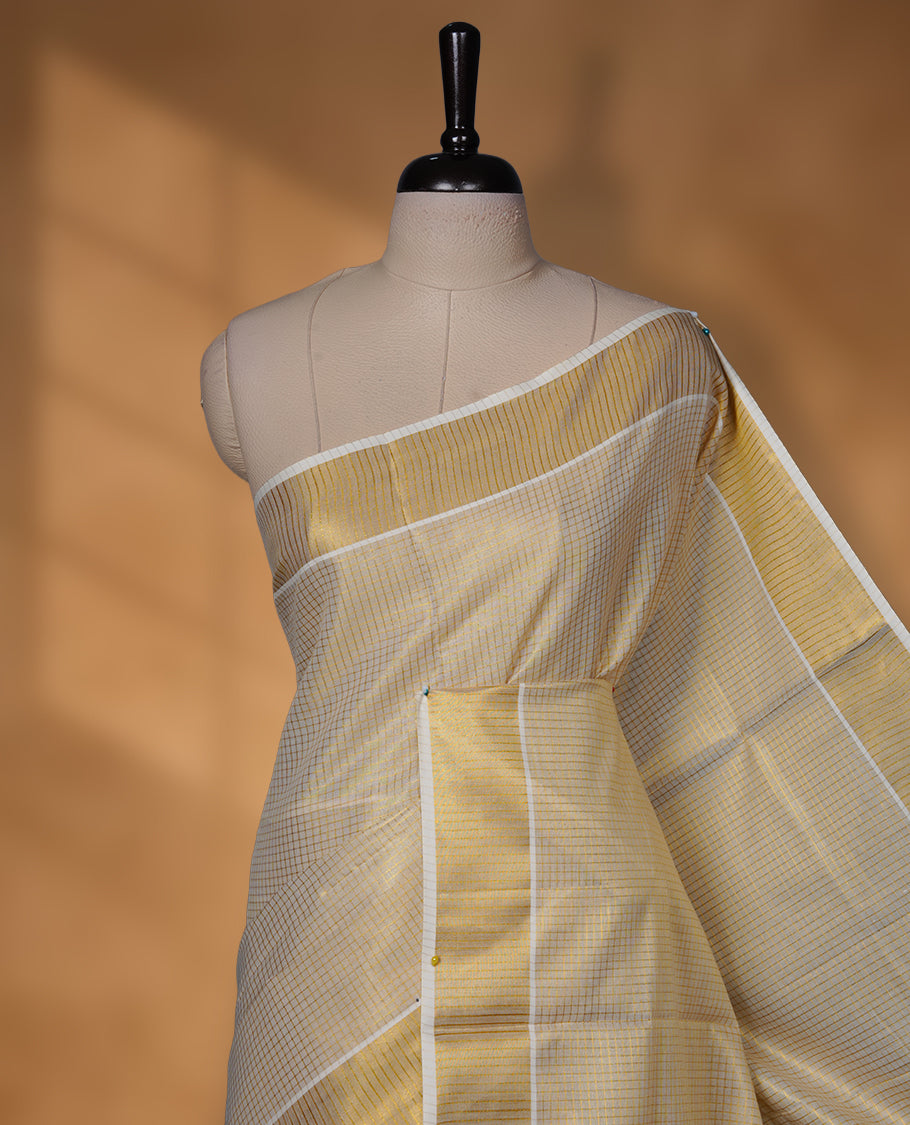 Off-white colour tissue Kerala saree featuring subtle gold checks throughout the body, finished with a classic gold kasavu border and a graceful pallu, paired with a matching blouse.