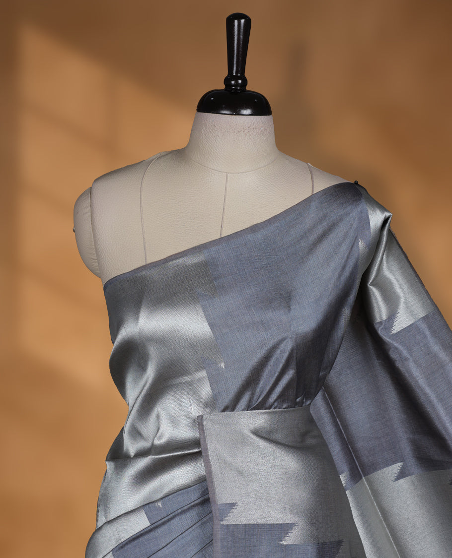 Gray and silver colour dual tone semi tussar saree featuring woven abstract geometric motifs on the body, complemented by a ikat inspired contrast olive patterned pallu, paired with a matching blouse.