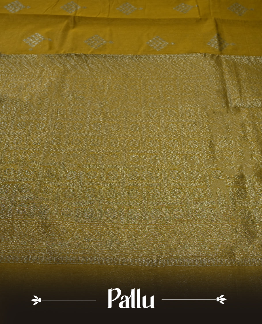 Bronze yellow colour silk cotton saree adorned with silver zari buttas and a rich zari border, complemented by a finely woven pallu & Paired with a matching blouse, perfect for festive gatherings and traditional occasions.