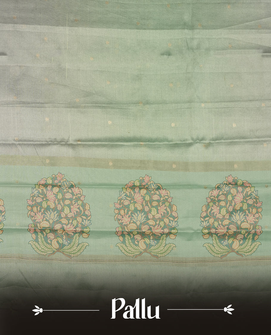 Silver colour semi tussar saree adorned with gold zari motifs across the body and Floral pattern contrast Aqua green colour on border, paired with a matching blouse.