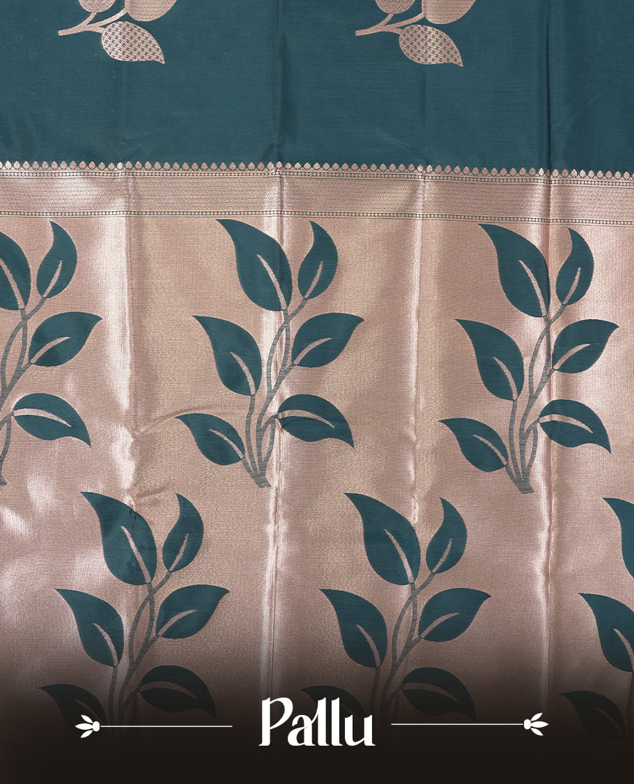 Dark teal blue colour semi silk saree adorned with elegant floral motifs on the body, complemented by a shimmering golden zari-woven pallu and border, and paired with a matching blouse