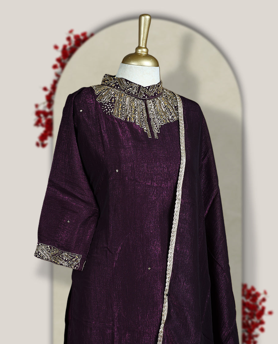 Deep wine colour churidar set with a rich sheen, beautifully adorned with golden cut beads work on the neckline and sleeve borders, Paired with a matching dupatta featuring a subtle zari edge, perfect for a regal festive look.